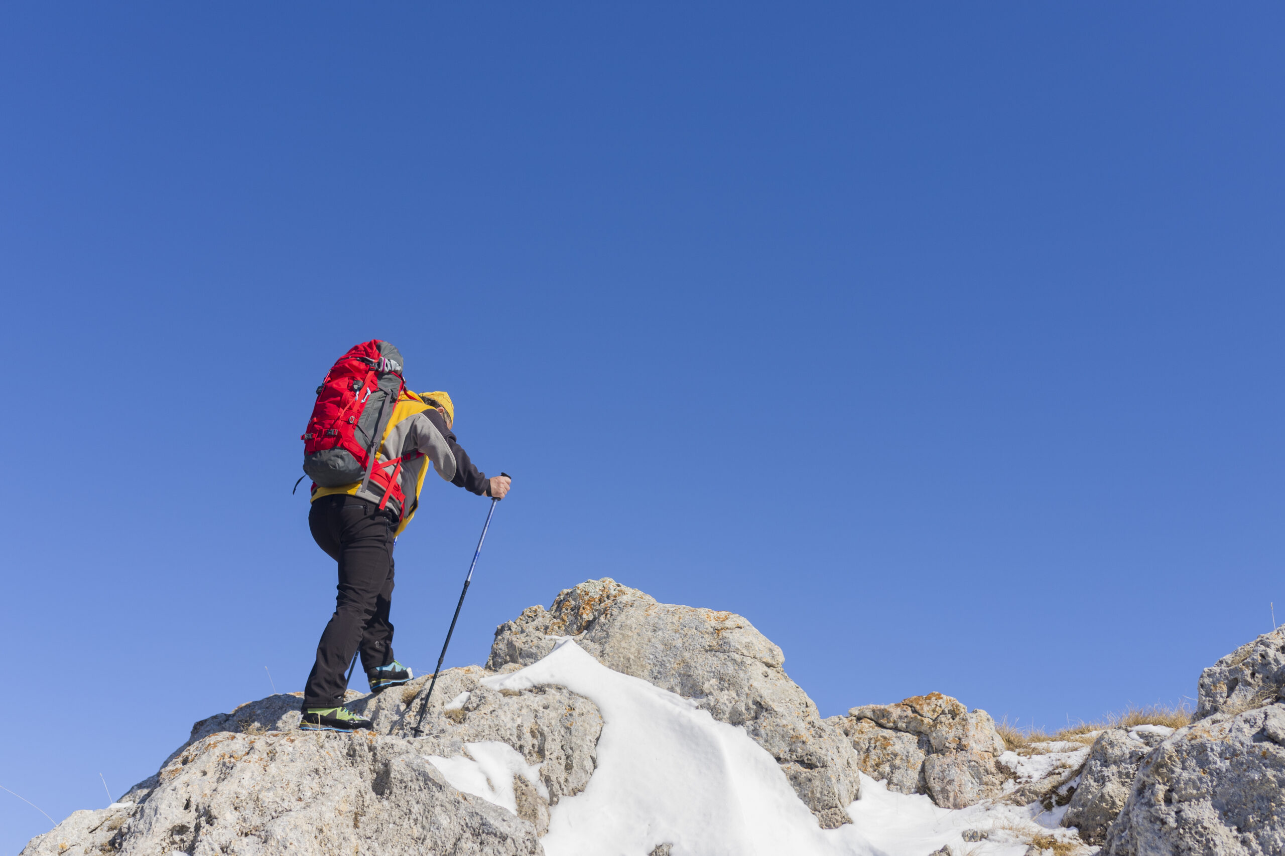 A back view of a hiker looking at the view from a snowy mountain peak